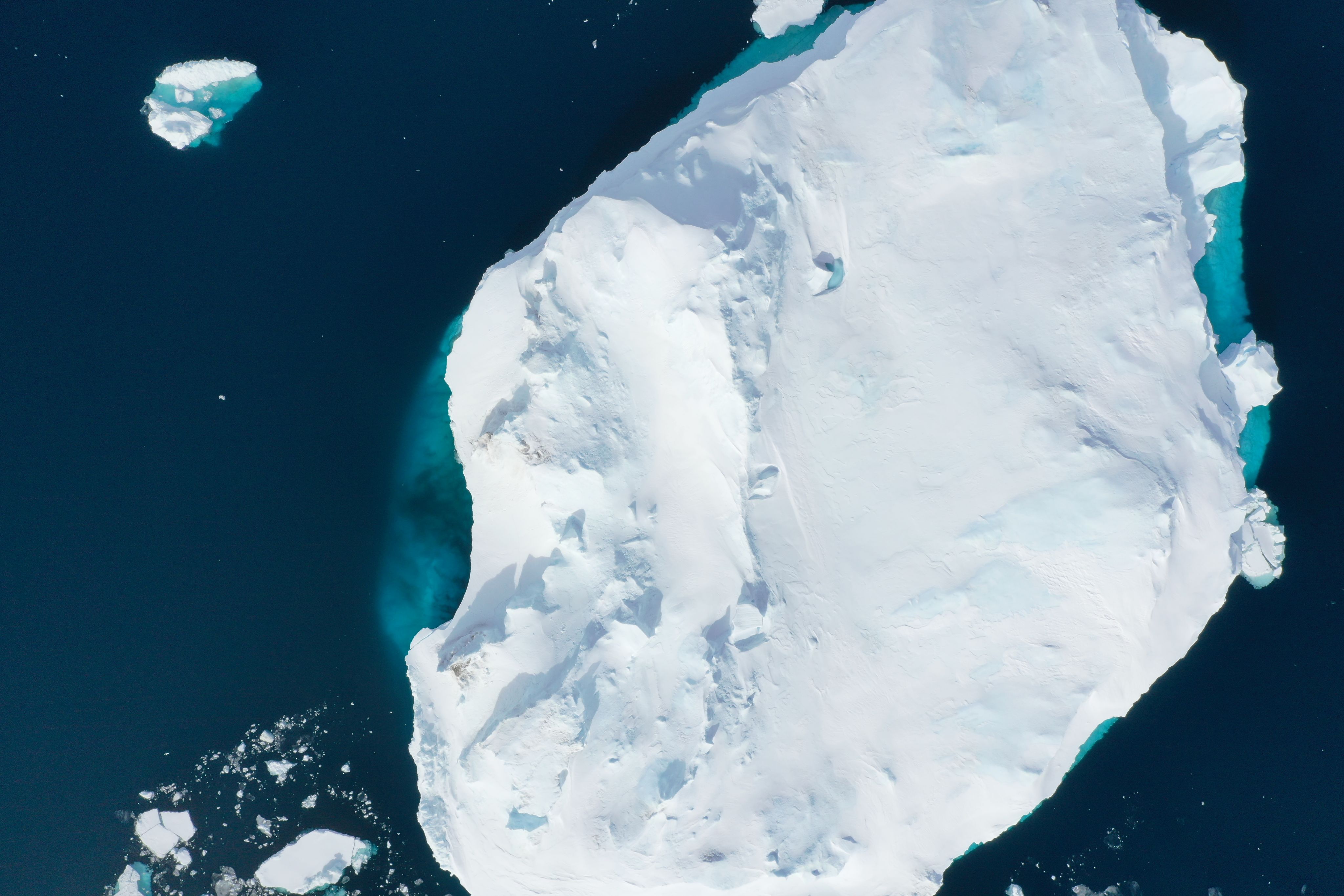 An iceberg and the deep blue sea. The submerged pat of the iceberg can be seen near the surface of the water. the water.