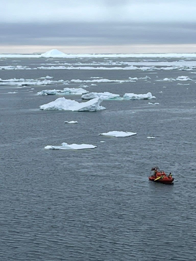 A small orange ship in an ice strewn sea collecting the yellow ocean gliders.