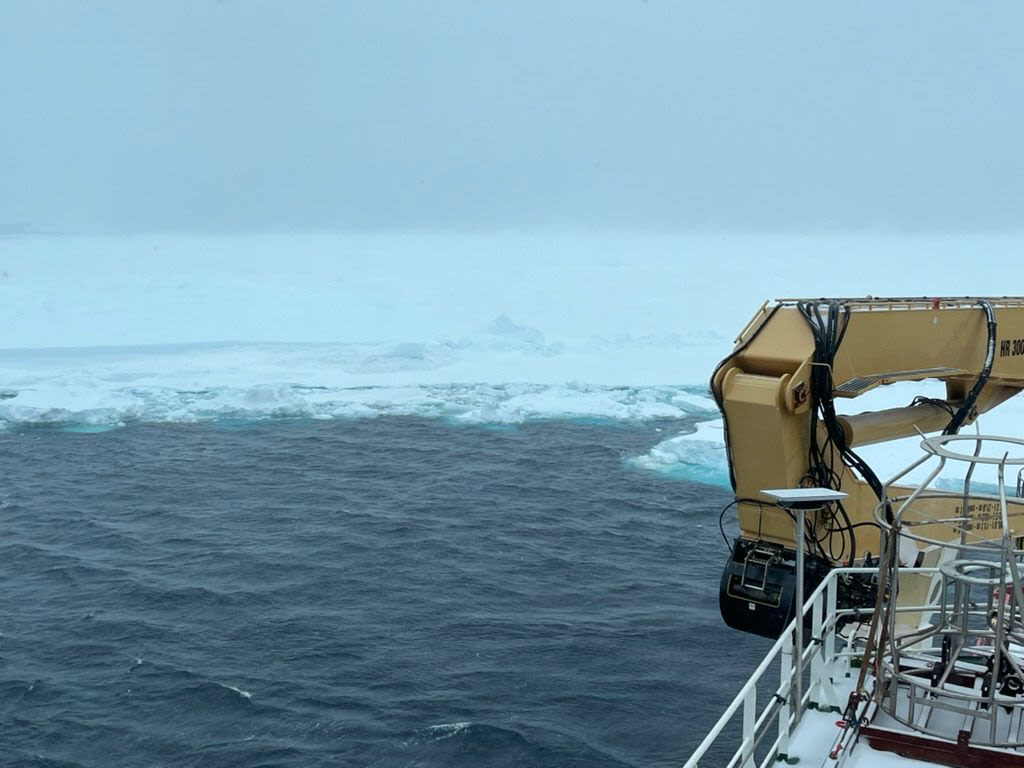 A huge wall of ice from the horizon can be seen advancing towards the ship.