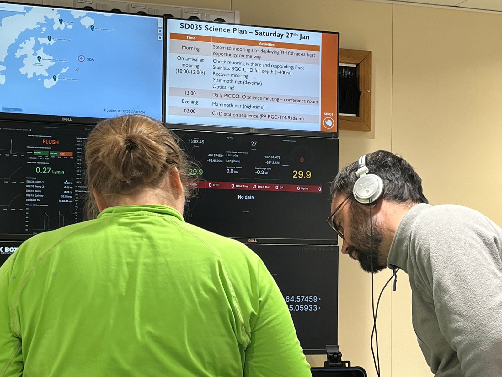 Sophie Fielding and Gareth Flint listening for the mooring. A large screen in front of them. Gareth is wearing headphones.