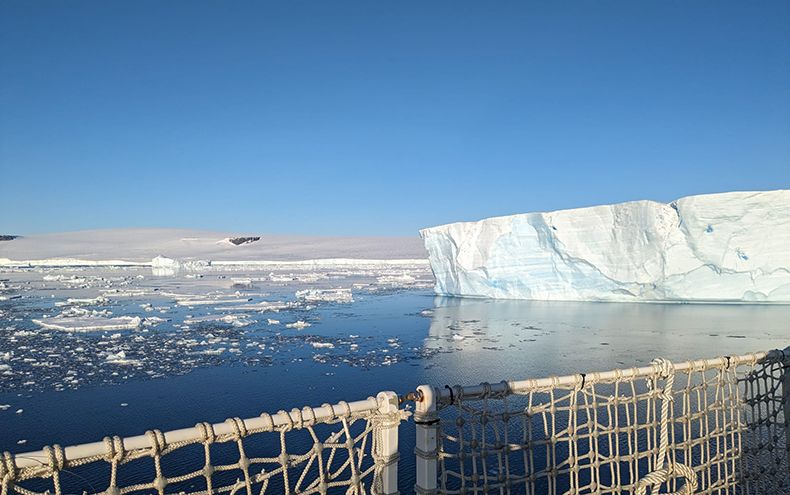 A view of an Antarctic ice shelf with a clear blue sky in the background.